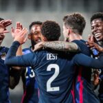 United States Men's National Soccer Team players celebrating victory wearing red white and blue uniforms